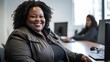 Dark skinned plus-size, overweight beautiful large female businesswoman using laptop at desk in modern office