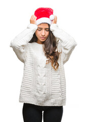 Wall Mural - Young arab woman wearing christmas hat over isolated background suffering from headache desperate and stressed because pain and migraine. Hands on head.