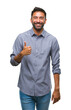 © Krakenimages.com - Adult hispanic man over isolated background doing happy thumbs up gesture with hand. Approving expression looking at the camera with showing success.