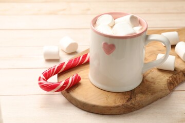 Sticker - Tasty hot chocolate with marshmallows and candy cane on light wooden table, closeup