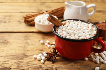 Wall Mural - Tasty hot chocolate with marshmallows and ingredients on wooden table, closeup. Space for text