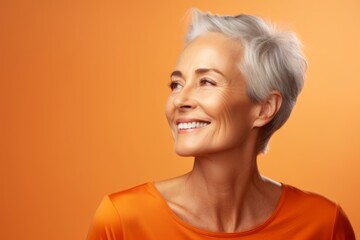 Wall Mural - beauty, people and health concept - smiling senior woman over orange background