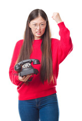 Canvas Print - Young Chinese woman over isolated background holding vintage telephone annoyed and frustrated shouting with anger, crazy and yelling with raised hand, anger concept