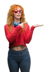 Poster - Young redhead woman wearing headphones very happy pointing with hand and finger