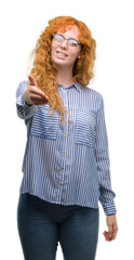 Poster - Young redhead bussines woman smiling friendly offering handshake as greeting and welcoming. Successful business.