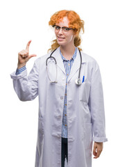 Sticker - Young redhead woman wearing doctor uniform smiling and confident gesturing with hand doing size sign with fingers while looking and the camera. Measure concept.