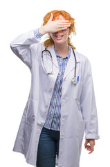 Sticker - Young redhead woman wearing doctor uniform smiling and laughing with hand on face covering eyes for surprise. Blind concept.