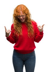 Poster - Young redhead woman wearing red sweater shouting with crazy expression doing rock symbol with hands up. Music star. Heavy concept.