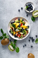 Wall Mural - Fruit and berry salad with mango, kiwi, apple, blueberry and fresh mint leaves. Healthy food, diet. Top view