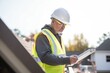 © studioworkstock - roofer checking material list on a tablet on the roof