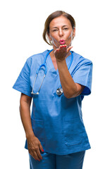 Poster - Middle age senior nurse doctor woman over isolated background looking at the camera blowing a kiss with hand on air being lovely and sexy. Love expression.