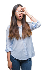 Wall Mural - Young asian business woman wearing glasses over isolated background doing ok gesture shocked with surprised face, eye looking through fingers. Unbelieving expression.