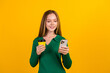 © deagreez - Photo of positive young teenager girl texting holding smartphone drink coffee takeout from cafeteria isolated on yellow color background