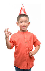 Wall Mural - Dark haired little child wearing birthday cap doing ok sign with fingers, excellent symbol