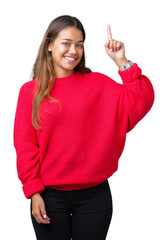 Canvas Print - Young beautiful brunette woman wearing red winter sweater over isolated background pointing finger up with successful idea. Exited and happy. Number one.