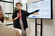 © AnnaStills - Female speaker with prosthetic arm presenting data of work results to colleague at business meeting