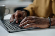 © AnnaStills - Closeup of hands of african american man typing on laptop keyboard while sitting at desk