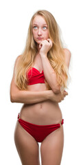 Sticker - Blonde teenager woman wearing red bikini with hand on chin thinking about question, pensive expression. Smiling with thoughtful face. Doubt concept.