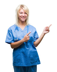 Sticker - Young beautiful blonde doctor woman wearing medical uniform over isolated background smiling and looking at the camera pointing with two hands and fingers to the side.