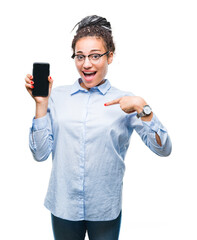 Wall Mural - Young braided hair african american business girl showing screen of smartphone over isolated background with surprise face pointing finger to himself