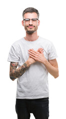 Wall Mural - Young tattooed adult man smiling with hands on chest with closed eyes and grateful gesture on face. Health concept.