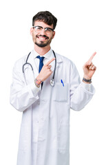 Canvas Print - Young doctor man wearing hospital coat over isolated background smiling and looking at the camera pointing with two hands and fingers to the side.