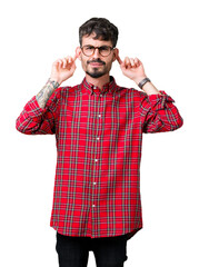 Sticker - Young handsome man wearing glasses over isolated background Smiling pulling ears with fingers, funny gesture. Audition problem