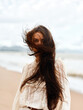 © SHOTPRIME STUDIO - Wind-blown Beauty: Young Attractive Woman with Long Flowing Hair, Enjoying Sunny Summer Day at the Beach.
