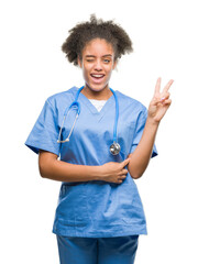 Sticker - Young afro american doctor woman over isolated background smiling with happy face winking at the camera doing victory sign. Number two.