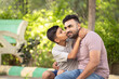 Happy indian son kissing his father while sitting at park - concept of affectionate, family relationship and joyful.