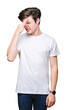 Young handsome man wearing casual white t-shirt over isolated background smelling something stinky and disgusting, intolerable smell, holding breath with fingers on nose. Bad smells concept.