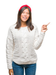 Sticker - Young asian woman wearing winter sweater over isolated background with a big smile on face, pointing with hand and finger to the side looking at the camera.