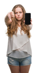 Poster - Young blonde woman using smartphone with angry face, negative sign showing dislike with thumbs down, rejection concept