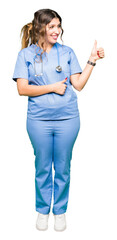 Canvas Print - Young adult doctor woman wearing medical uniform Looking proud, smiling doing thumbs up gesture to the side