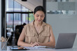 © Tj - Sharing good business news. Attractive young businesswoman talking on the mobile phone and smiling while sitting at her working place in office and looking at laptop PC.