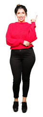 Sticker - Young beautiful woman wearing red sweater and bun with a big smile on face, pointing with hand and finger to the side looking at the camera.