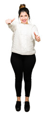 Sticker - Young beautiful woman wearing winter sweater approving doing positive gesture with hand, thumbs up smiling and happy for success. Looking at the camera, winner gesture.