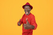 Ecstatic senior man in a red sweater and hat giving a thumbs up, his face beaming