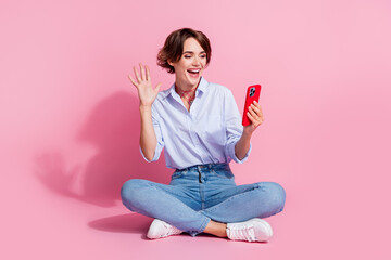 Poster - Full body photo of excited pretty lady sit floor hold smart phone take selfie record video arm wave hi isolated on pink color background