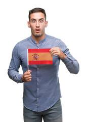 Sticker - Handsome young man holding a flag of Spain scared in shock with a surprise face, afraid and excited with fear expression