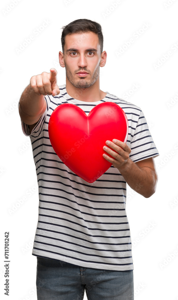 Handsome young man in love holding red heart pointing with finger to ...