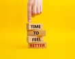 Time to feel better symbol. Wooden blocks with words Time to feel better. Businessman hand. Beautiful yellow background. Medicine and Time to feel better concept. Copy space.