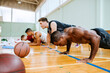 © Marko Geber - Diverse young men doing push ups in basketball gym