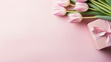 Fototapeta Tulipany - a Mother's Day concept, featuring a stylish pink gift box adorned with a ribbon bow and a bouquet of tulips on an isolated pastel pink background with ample copyspace.