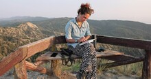 Young Woman Sitting On Bench Writing In Notebook At Vashlovani National Park In Georgia
