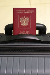 Wall Mural - Closeup view of russian passport and grey suitcase.