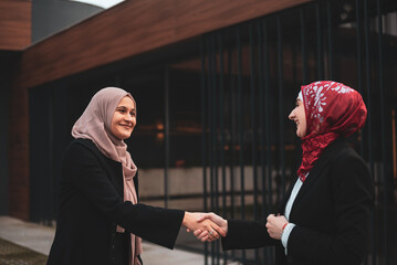 Wall Mural - Two successful business Muslim woman shaking hands finishing up meeting.