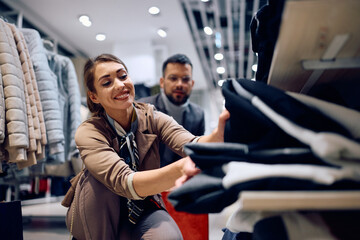 Wall Mural - Happy woman enjoying in buying clothing with her boyfriend in shopping mall.