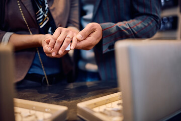 Wall Mural - Close up of couple buying engagement ring at jewelry store.