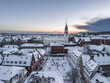 Aerial white winter cityscape of the Aalborg old town covered with snow. Christmas holiday outdoor skating rink at Budolfi Church (Budolfi Kirke). North Jutland, Denmark
